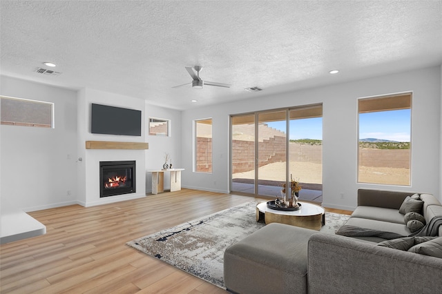 85 Cadena Blvd, Los Alamos, NM 87547 - living room featuring a ceiling fan, a textured ceiling, a glass covered fireplace, baseboards, and light wood finished floors