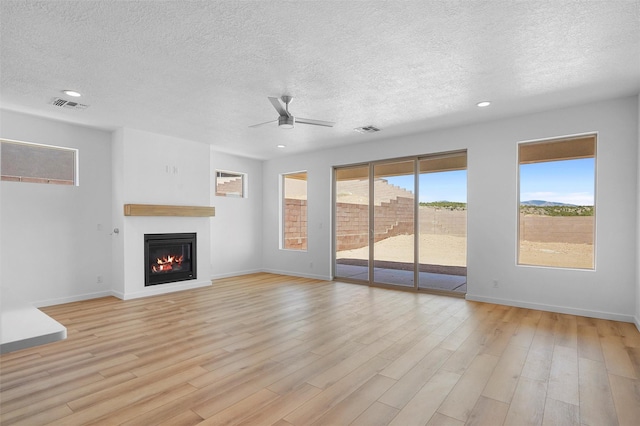 85 Cadena Blvd, Los Alamos, NM 87547 - unfurnished living room with a textured ceiling, ceiling fan, a glass covered fireplace, light wood-style flooring, and baseboards