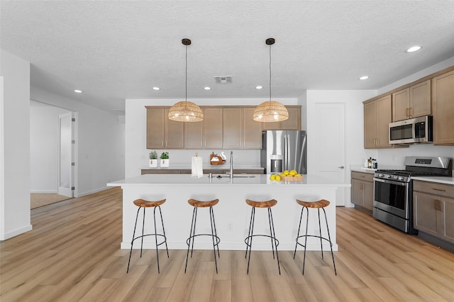85 Cadena Blvd, Los Alamos, NM 87547 - kitchen with stainless steel appliances, a sink, a breakfast bar, recessed lighting, and light wood-type flooring