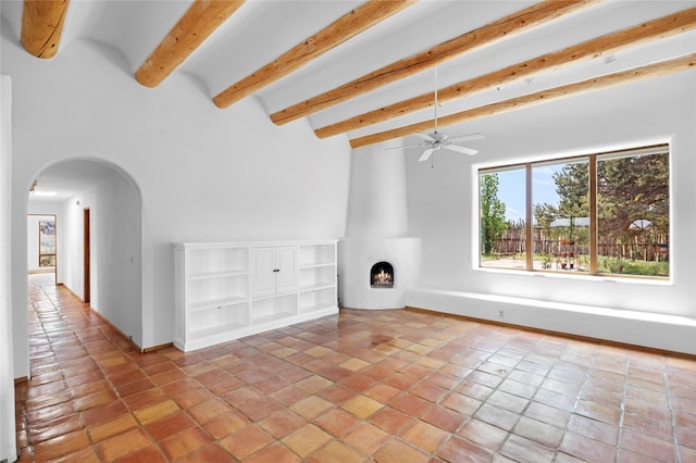 1 Azul Pl, Santa Fe, NM 87508 - unfurnished living room with arched walkways, beam ceiling, a large fireplace, light tile patterned flooring, and ceiling fan
