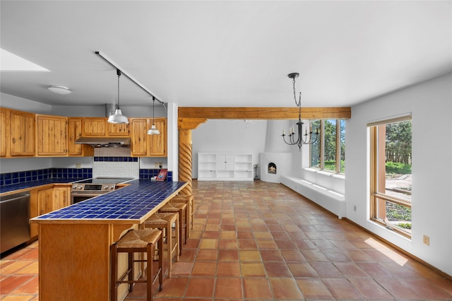 1 Azul Pl, Santa Fe, NM 87508 - kitchen with stainless steel appliances, tile countertops, under cabinet range hood, a kitchen bar, and a chandelier