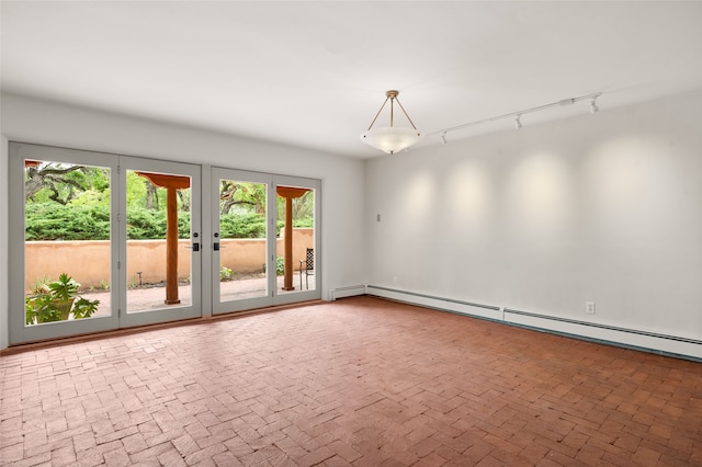 spare room with healthy amount of natural light, a baseboard radiator, and brick flooring