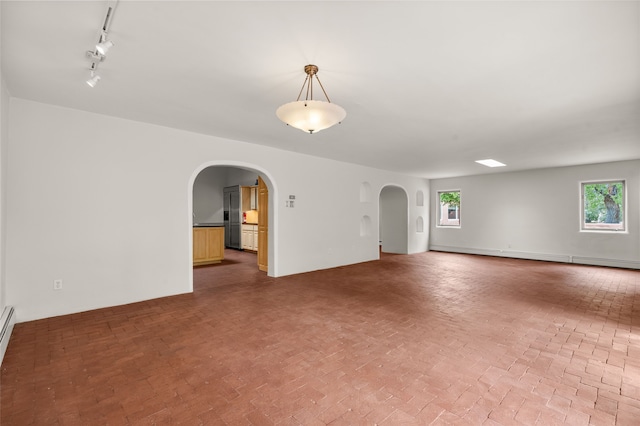 unfurnished room with arched walkways, rail lighting, and a baseboard radiator