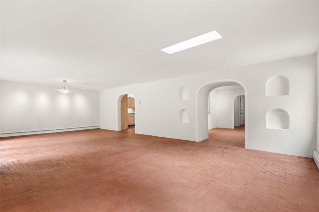 empty room with arched walkways, brick floors, and baseboard heating