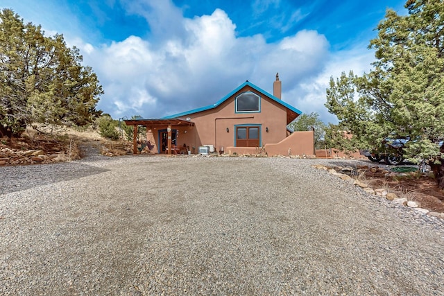 25A Lime Kiln Rd, Lamy, NM 87540 - view of front of home featuring a chimney, stucco siding, and gravel driveway