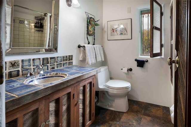 942 Canyon Unit A & B, Santa Fe, NM 87501 - bathroom with stone finish flooring, toilet, vanity, tiled shower, and baseboards
