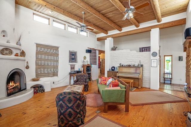 24 Camino Caballos Spur, Lamy, NM 87540 - living room with a lit fireplace, wooden ceiling, a ceiling fan, beamed ceiling, and a towering ceiling