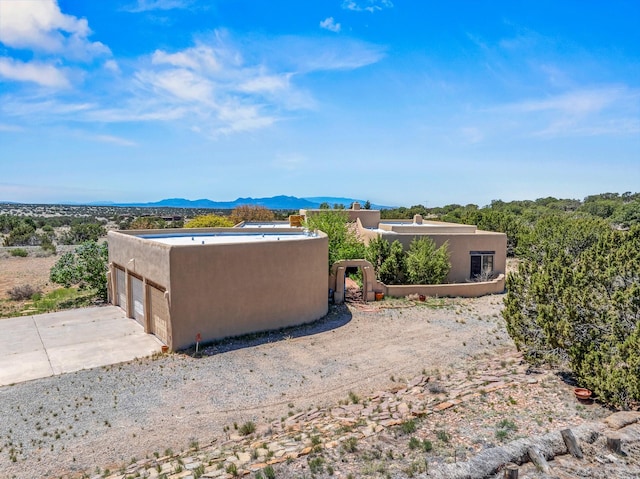 24 Camino Caballos Spur, Lamy, NM 87540 - view of side of property with stucco siding, a mountain view, and a garage