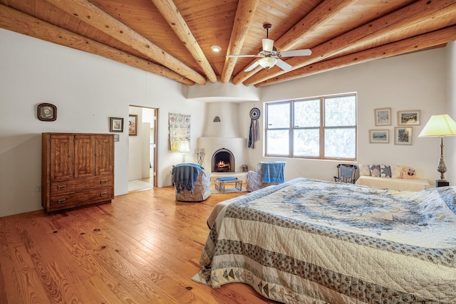 24 Camino Caballos Spur, Lamy, NM 87540 - bedroom with beam ceiling, a warm lit fireplace, light wood finished floors, and wooden ceiling