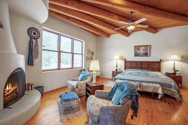 24 Camino Caballos Spur, Lamy, NM 87540 - bedroom featuring wooden ceiling, beam ceiling, hardwood / wood-style floors, and a tiled fireplace