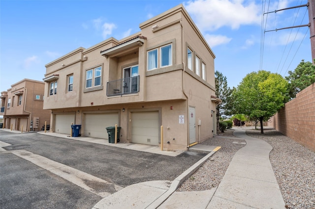 4315 Santo Domingo Unit C, Santa Fe, NM 87507 - rear view of house with stucco siding, an attached garage, a balcony, and fence