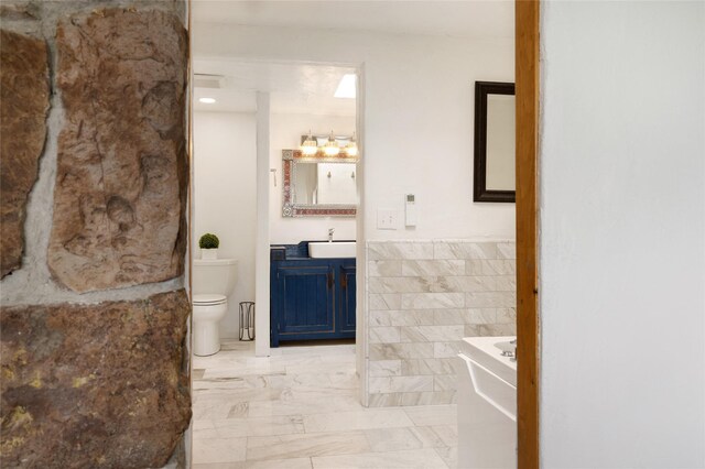 100 Rancho Alegre, Santa Fe, NM 87508 - bathroom featuring toilet, vanity, a wainscoted wall, tile walls, and marble finish flooring