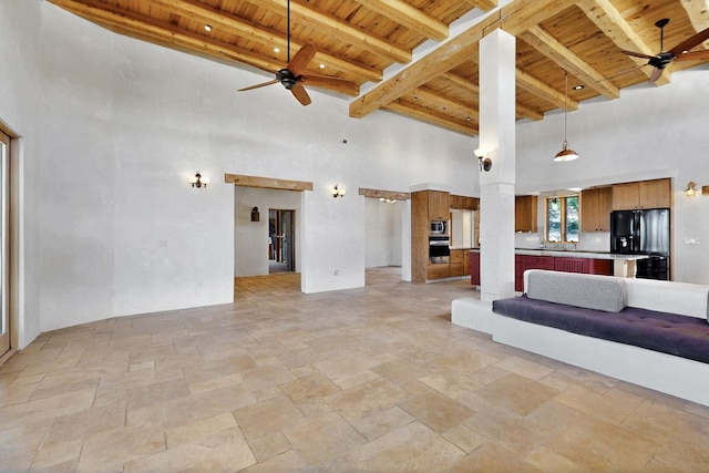 5 Camino Sin Ganas, Santa Fe, NM 87506 - unfurnished living room with wooden ceiling, a ceiling fan, beamed ceiling, stone tile floors, and a towering ceiling