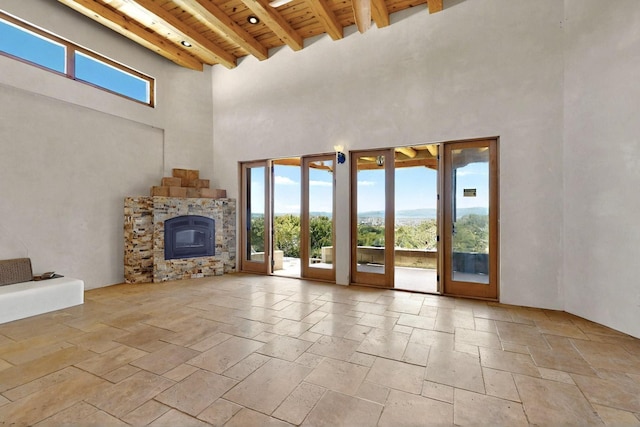 5 Camino Sin Ganas, Santa Fe, NM 87506 - unfurnished living room featuring wood ceiling, beam ceiling, a towering ceiling, and stone tile floors