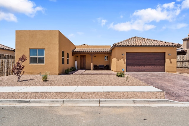 35 La Pradera, Santa Fe, NM 87508 - view of front facade with stucco siding, a garage, decorative driveway, a tile roof, and fence