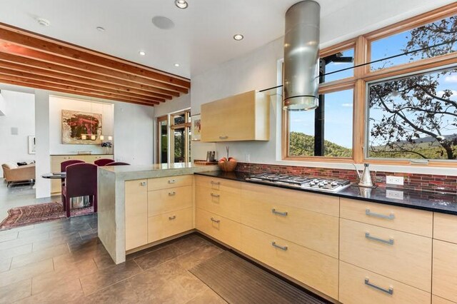 kitchen with appliances with stainless steel finishes, a sink, light brown cabinets, a wall mounted AC, and tasteful backsplash