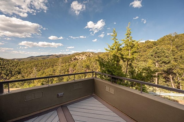 wooden terrace featuring a forest view and a mountain view
