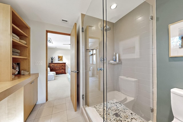 ensuite bathroom with a shower stall, tile patterned floors, and toilet