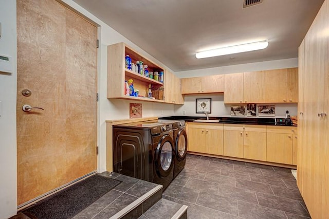 washroom featuring independent washer and dryer, cabinet space, and stone finish flooring