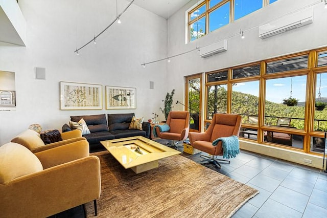 living area with a high ceiling, tile patterned flooring, a wall mounted air conditioner, and rail lighting