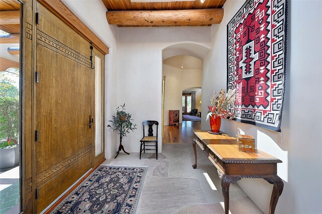 foyer with arched walkways, wood ceiling, and beam ceiling