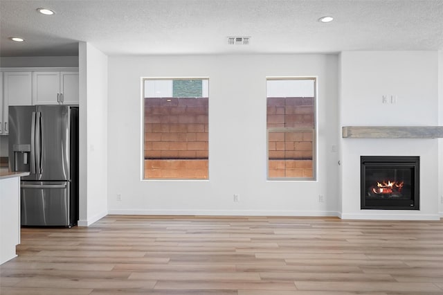137 Mirador Blvd, Los Alamos, NM 87547 - unfurnished living room with light wood-type flooring, a textured ceiling, recessed lighting, baseboards, and a glass covered fireplace