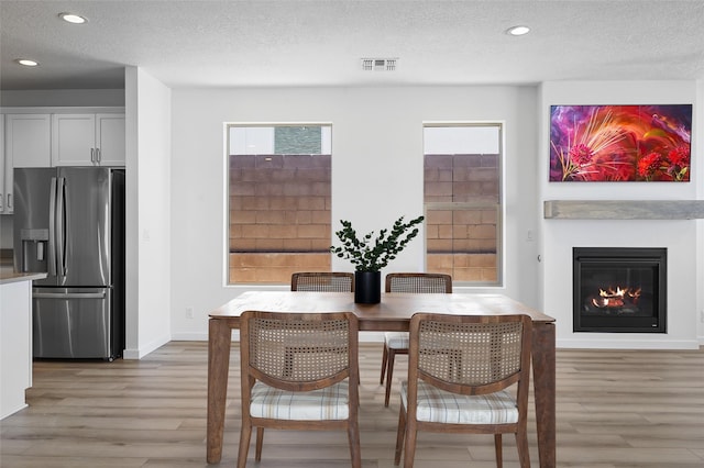 137 Mirador Blvd, Los Alamos, NM 87547 - dining space featuring light wood finished floors, a textured ceiling, recessed lighting, baseboards, and a glass covered fireplace