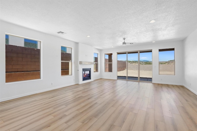 137 Mirador Blvd, Los Alamos, NM 87547 - unfurnished living room with a textured ceiling, light wood-type flooring, a ceiling fan, baseboards, and a glass covered fireplace