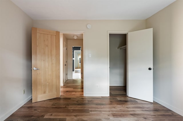 928 Los Lovatos Rd, Santa Fe, NM 87501 - unfurnished bedroom featuring wood finished floors, a closet, and baseboards