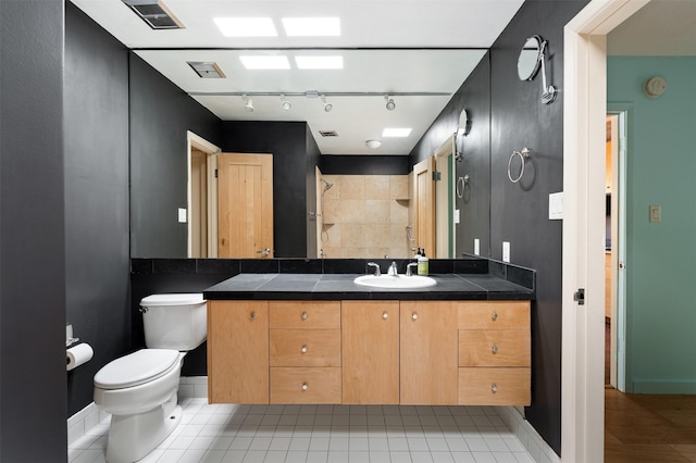 928 Los Lovatos Rd, Santa Fe, NM 87501 - bathroom featuring toilet, vanity, tiled shower, baseboards, and track lighting