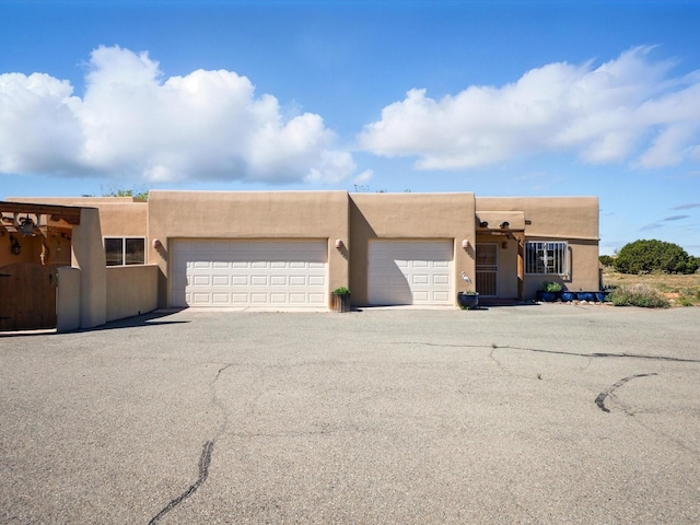 54 Encantado Loop, Santa Fe, NM 87508 - adobe home featuring a garage, stucco siding, and driveway