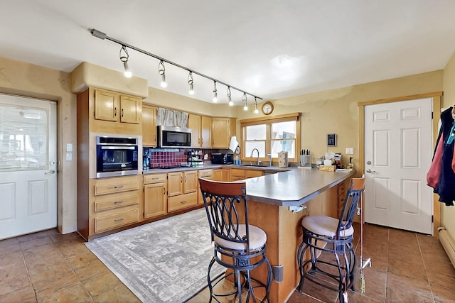 26 Apache Creek Rd, Santa Fe, NM 87505 - kitchen with stainless steel appliances, a sink, a peninsula, a breakfast bar area, and light brown cabinetry