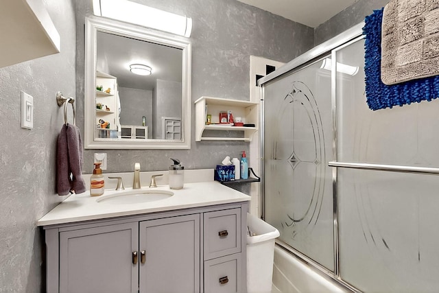 26 Apache Creek Rd, Santa Fe, NM 87505 - full bath featuring a textured wall, vanity, and combined bath / shower with glass door