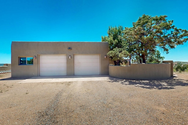 26 Apache Creek Rd, Santa Fe, NM 87505 - view of front of home with stucco siding, dirt driveway, and fence