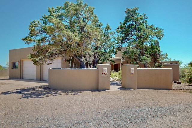 26 Apache Creek Rd, Santa Fe, NM 87505 - view of front of house featuring a fenced front yard, a garage, concrete driveway, a gate, and stucco siding