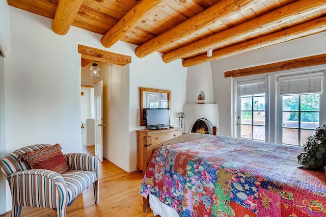 334 Otero Unit 14-3, Santa Fe, NM 87501 - bedroom with light wood-style floors, access to outside, a large fireplace, beam ceiling, and wood ceiling