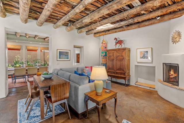 127 County Road 84, Santa Fe, NM 87506 - living room featuring finished concrete floors, wood ceiling, beamed ceiling, and a warm lit fireplace