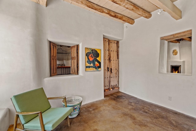 127 County Road 84, Santa Fe, NM 87506 - living area featuring concrete floors, wood ceiling, beam ceiling, and a warm lit fireplace