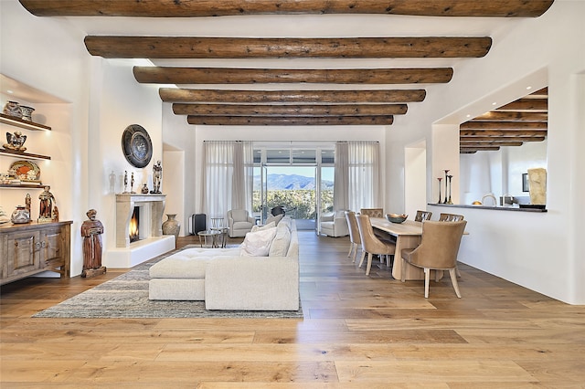 3289 Monte Sereno, Santa Fe, NM 87506 - living area with beamed ceiling, hardwood / wood-style flooring, and a lit fireplace