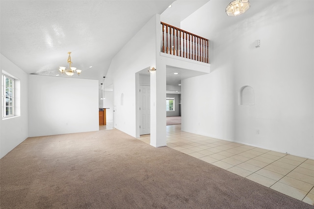 1905 Mendius, Los Alamos, NM 87544 - unfurnished living room with a chandelier, light tile patterned flooring, light carpet, and lofted ceiling