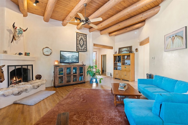 2 Tierra Grande, Santa Fe, NM 87506 - living area with wooden ceiling with exposed beams, ceiling fan, wood finished floors, and a warm lit fireplace
