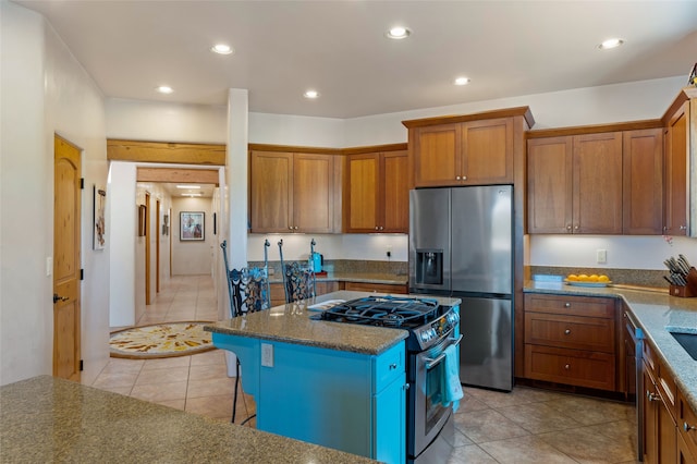 2 Tierra Grande, Santa Fe, NM 87506 - kitchen with appliances with stainless steel finishes, light tile patterned floors, brown cabinetry, a kitchen breakfast bar, and a center island