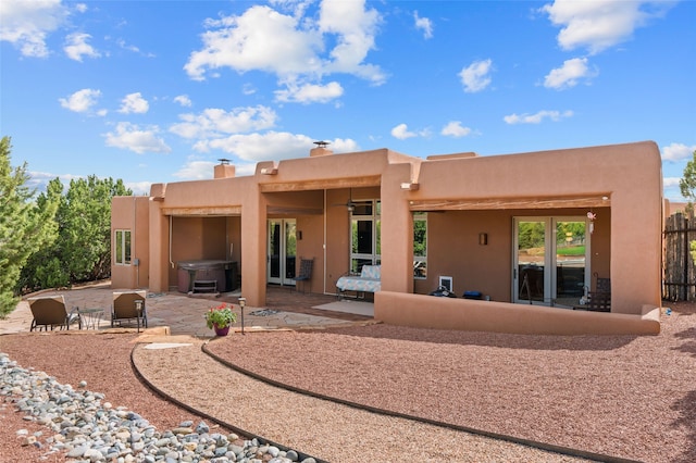 2 Tierra Grande, Santa Fe, NM 87506 - back of property with a hot tub, a patio area, stucco siding, and a chimney