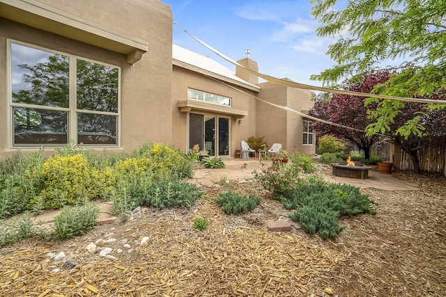 4548 Contenta Rdg, Santa Fe, NM 87507 - rear view of house featuring an outdoor fire pit, stucco siding, and a chimney