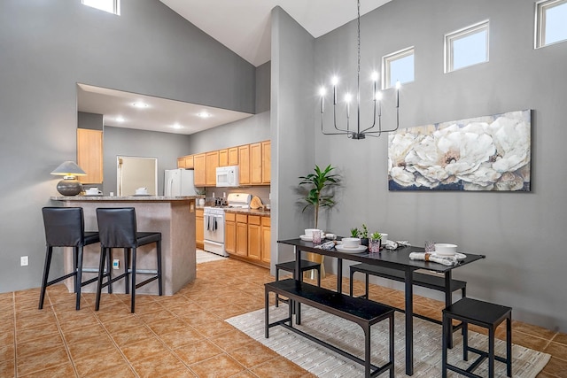 4548 Contenta Rdg, Santa Fe, NM 87507 - kitchen with white appliances, a towering ceiling, a chandelier, light brown cabinets, and a kitchen breakfast bar