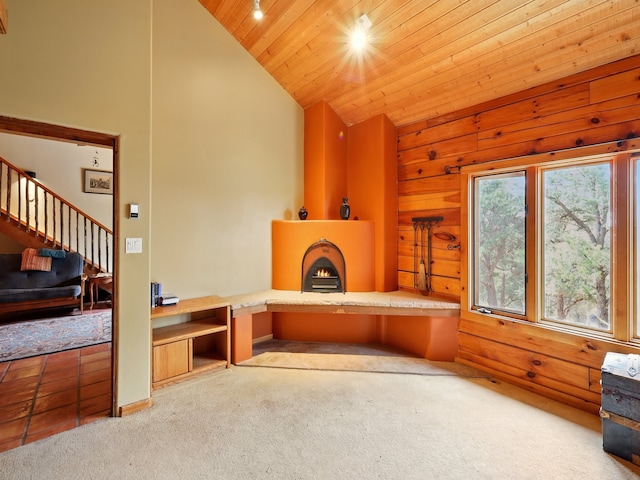 125 Apache Canyon Trl, Santa Fe, NM 87505 - unfurnished living room with carpet, wood ceiling, wood walls, stairway, and a lit fireplace
