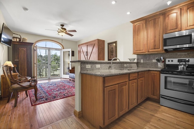 44 Sage Ln Unit 212, Angel Fire, NM 87710 - kitchen featuring stainless steel appliances, a peninsula, dark stone counters, ceiling fan, and hardwood / wood-style floors