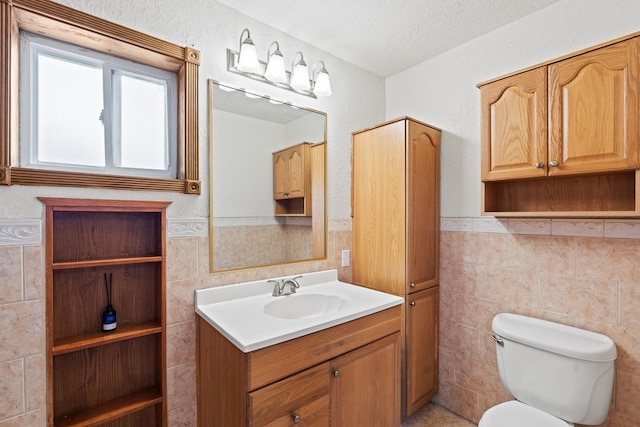 1024 Camino Vista Aurora, Santa Fe, NM 87507 - bathroom with tile walls, vanity, toilet, wainscoting, and a textured ceiling