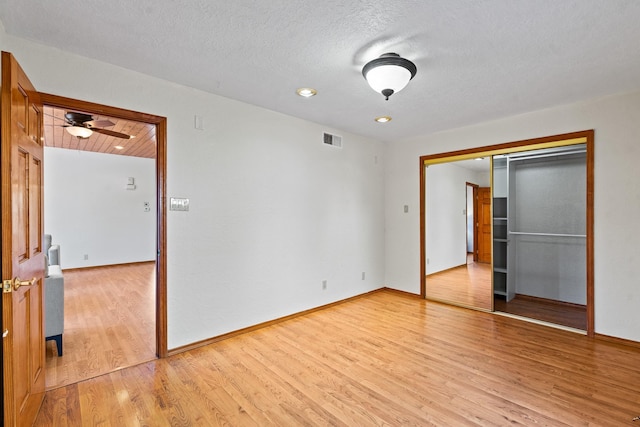 1024 Camino Vista Aurora, Santa Fe, NM 87507 - unfurnished bedroom featuring light wood-style floors, a closet, baseboards, and a textured ceiling