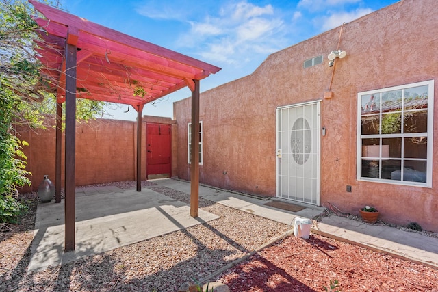 1024 Camino Vista Aurora, Santa Fe, NM 87507 - view of exterior entry with stucco siding, a pergola, and a patio area